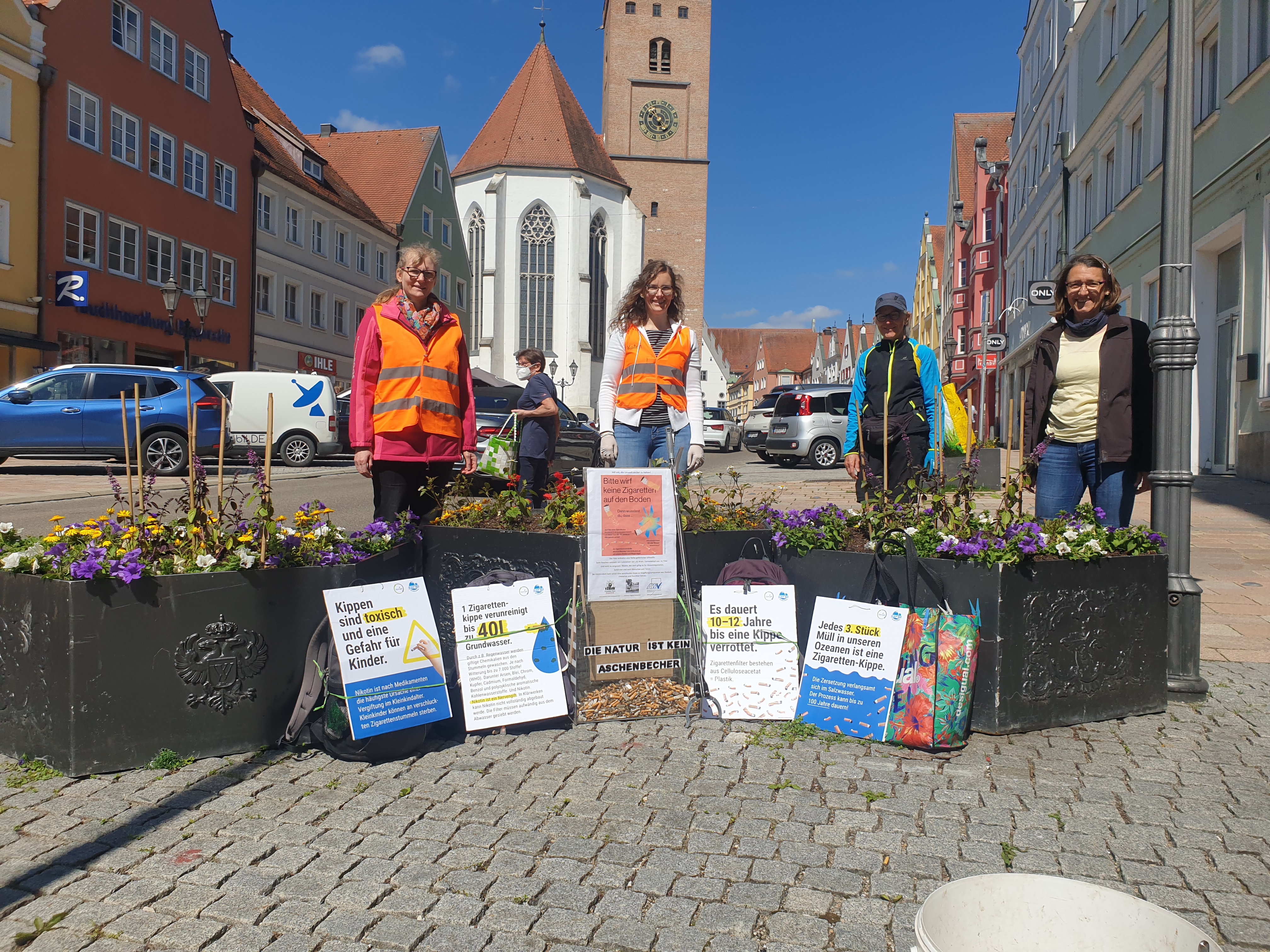 Vier Frauen stehen vor Blumenbeeten und machen Werbung für Nichtrauchen.