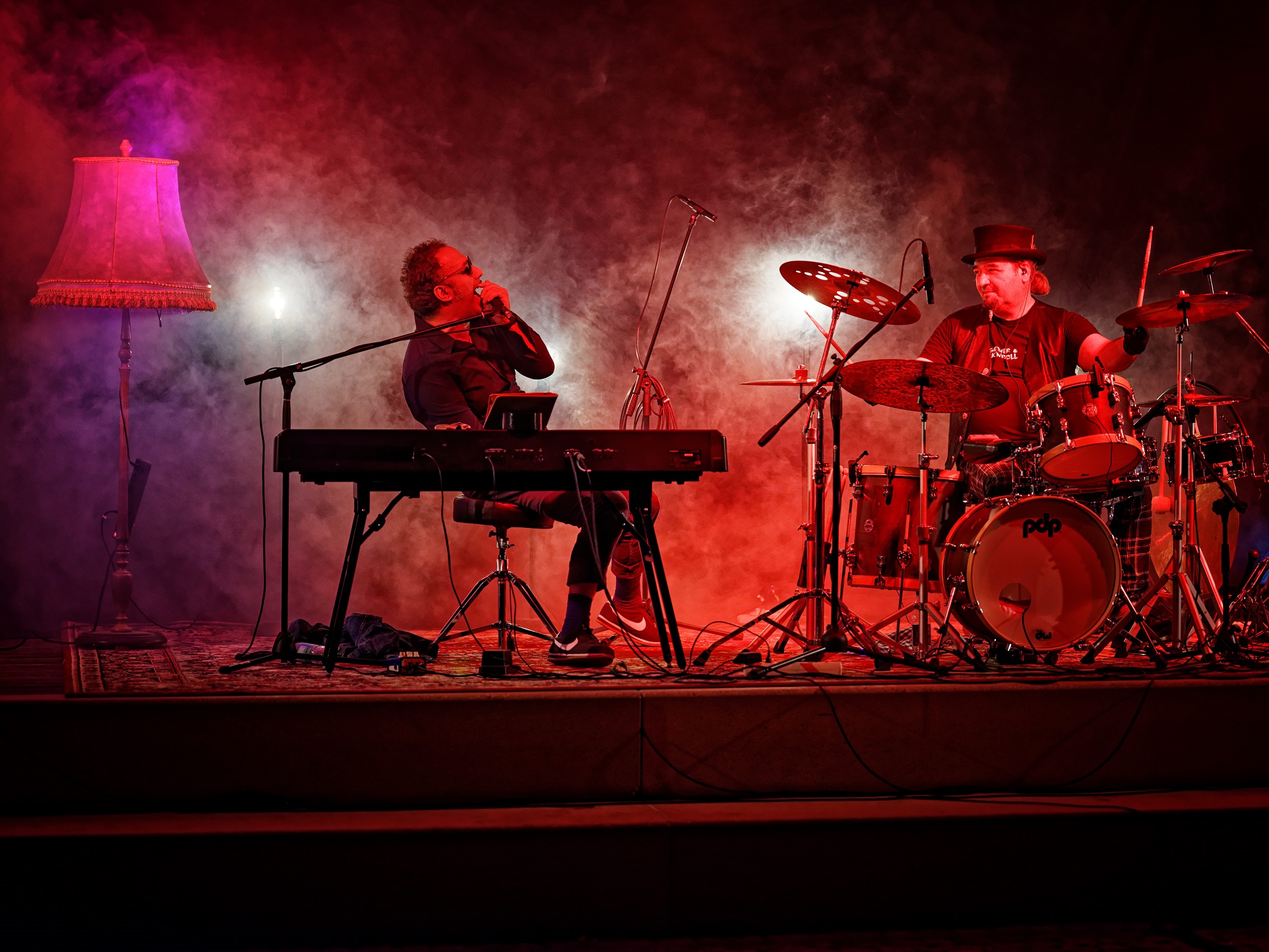 Keyboarder und Schlagzeuger auf Bühne in rot-lila Licht und Nebel