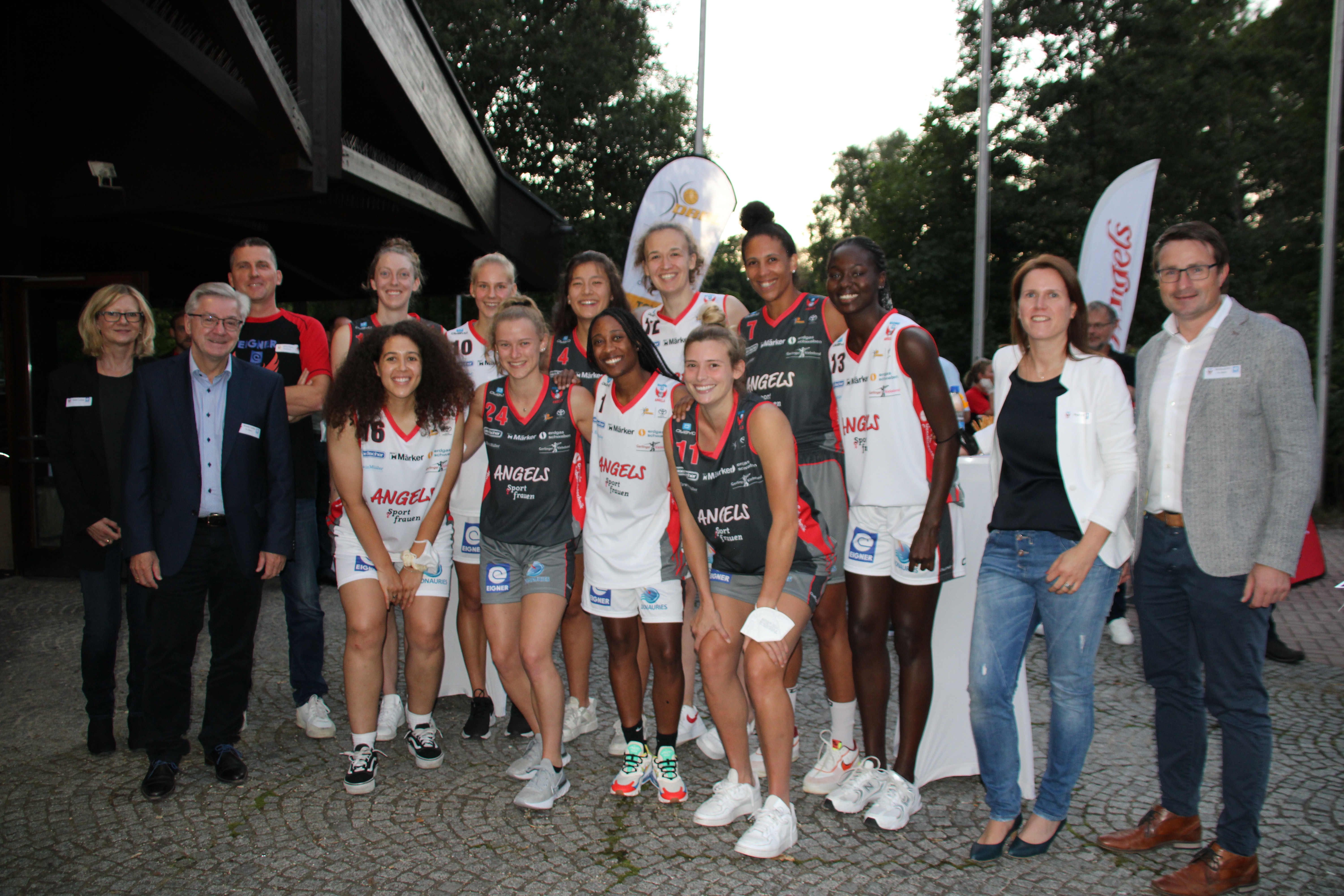 Basketballerinnen in Trikots mit Coach und Sponsoren