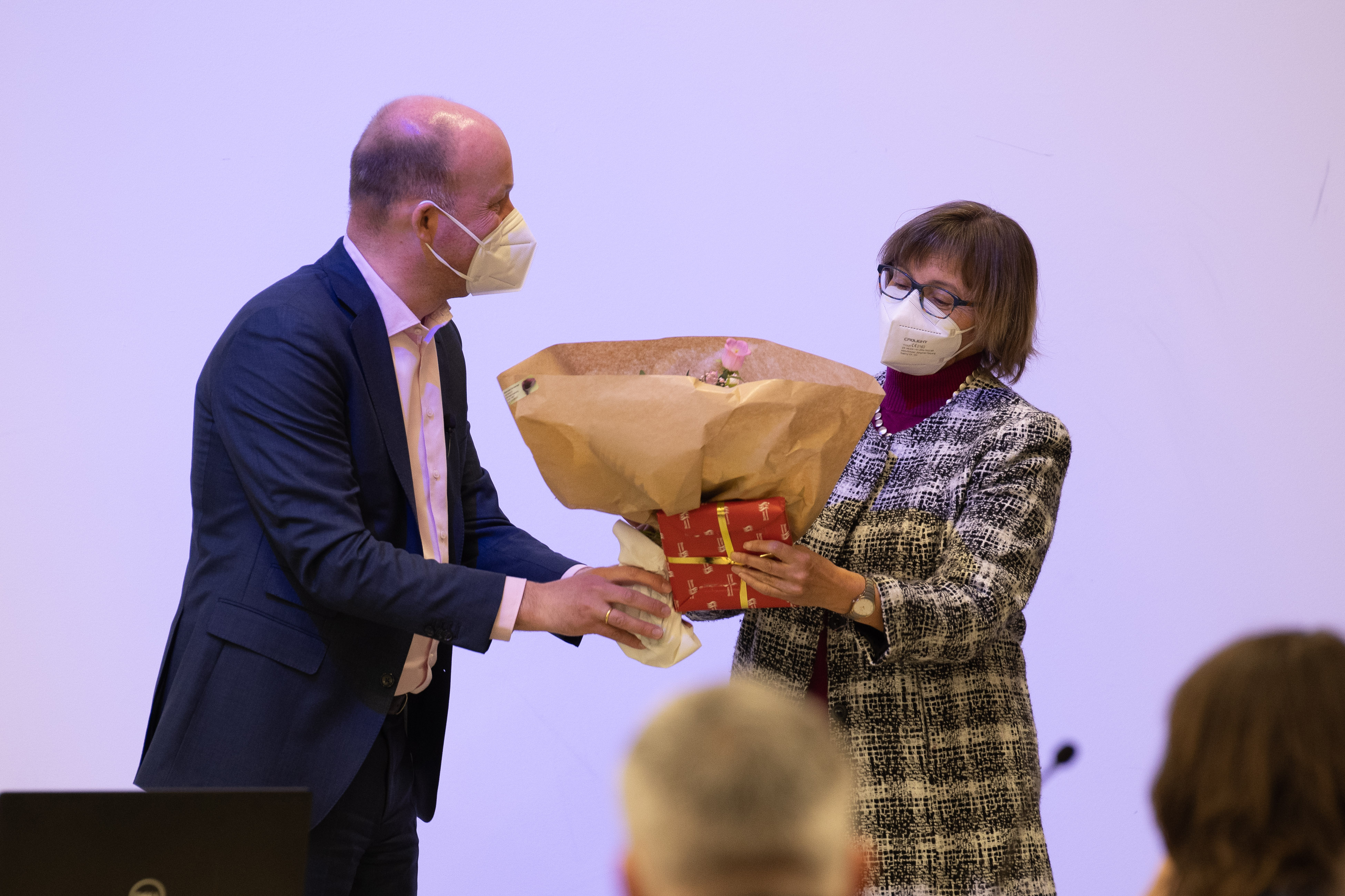 Blumen und ein verpacktes Geschenk werden an Dr. Ruth Kilian übergeben.