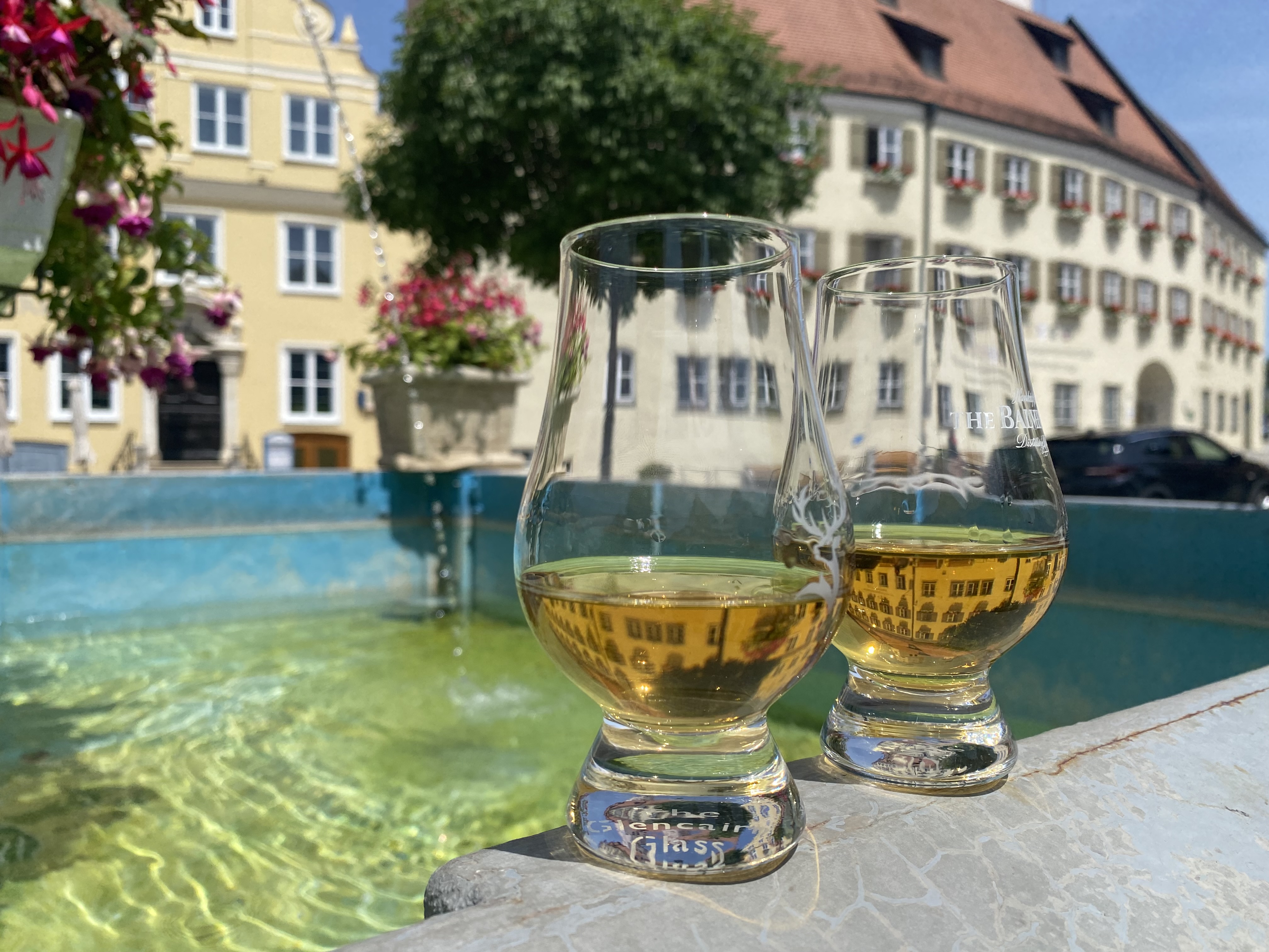 zwei whisky gläser an einem brunnen
