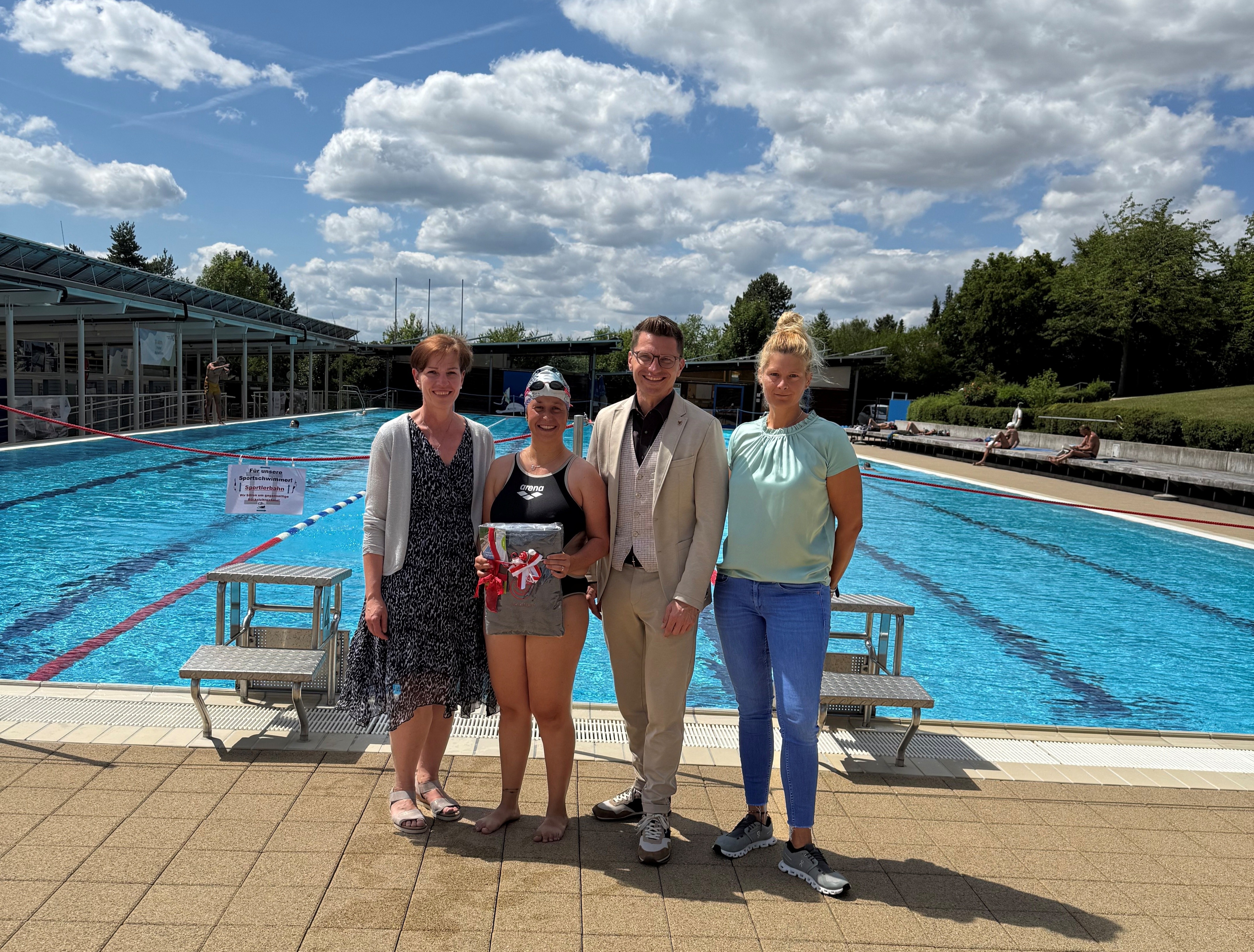 Oberbürgermeister David Wittner (2. v. r.), Simone Leidel (links, stellvertretende Leitung des Sachgebiets Liegenschaften, Schulen, Sport) und Nicole Hofmann (rechts, stellvertretende Betriebsleiterin der Bäder) gratulieren der 50.000. Besucherin Lena Steinle (2. v. l.).