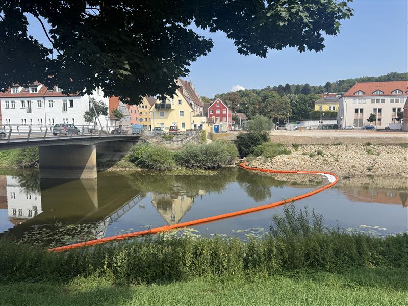 Die Feuerwehr will durch Barrikaden ein Eindringen des Ölteppichs in die Wörnitz verhindern.