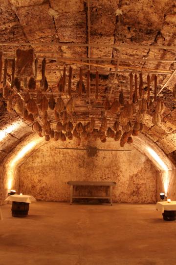 Schinken hängt von der Decke eines Kellers. 