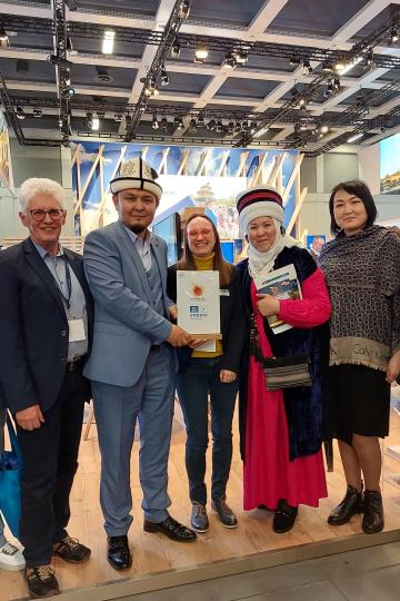 Günter Zwerger mit Abdulkadir Aliev (Direktor der Tourismusbehörde in der Oblast-Verwaltung Osh und aktiver Förderer des Geoparks Madygen in den Regionen Batken und Osh) im blauen Anzug; daneben Heike Burkhardt,  Jyldyz Asanakunova (Vorsitzende der Tourismusbehörde in der Destination South Shore am Südufer des Issyk-Kul-Sees und engagierte Förderin eines noch zu benennenden Geoparks dort) und ganz rechts Aida Rakhmanova, die zuständig für Soziales in der Oblast-Verwaltung der Destination Osh). 