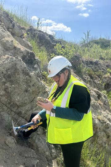 Silke Asche untersucht einen Gesteinsbrocken, den die NASA-Wissenschaftlerin kurz zuvor aus der Wand des Steinbruchs gelöst hat.