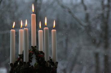 Das Bild zeigt Kerzen im Schnee. 