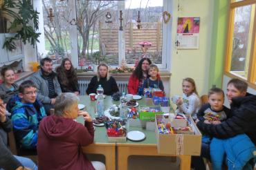 Menschen mit Behinderung und Kindern sitzen gemeinsam beim Adventskaffee. 
