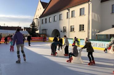Kinder fahren Schlittschuh vor dem Rainer Schloss. 