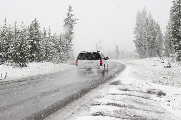 Das Bild zeigt ein Auto, das auf einer Schneebedeckten Straße fährt. 