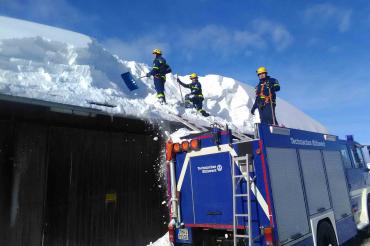 Die Männer des THWs räumen den Schnee von den Dächern