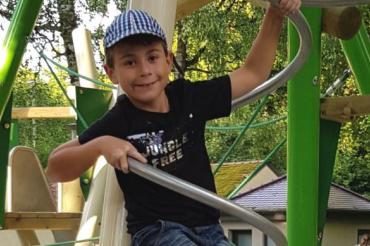 Das Bild zeigt einen Jungen auf einen Klettergerüst. 