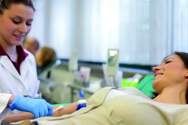 Frau auf Liege wird Blut abgenommen