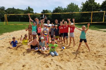 Auf dem Bild zu sehen sind Kinder, im Rahmen des Ferienprogramms, auf dem Volleyballfeld. 