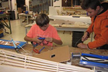 Das Bild zeigt Jugendlichen in der Jugendwerkstatt der Flugmodellgruppe beim Bauen von Modellfliegern