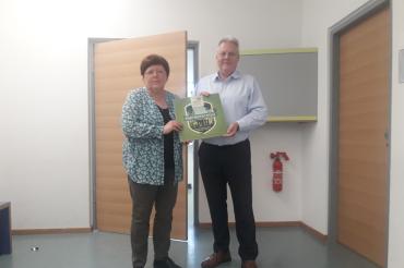 Erika Wiedemann, die Organisatorin der Haussammlung überreicht Schulleiter Robert Böse die von Alexander Helber, dem 1. Vorsitzenden BN Donau-Ries, erhaltene Auszeichnung. 