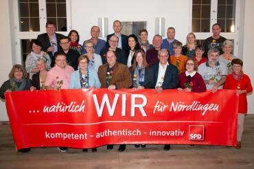 SPD-kandidaten mit Rose hinter einem SPD-Banner