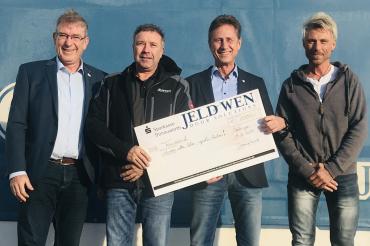 Vier Männer mit Scheck bei einer Spendenübergabe