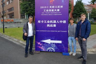 Josef Wolf, Richard Haas und Florian Knie stehen vor einem Schild mit chinesischen Schriftzeichen