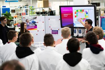 Das Bild zeigt v.l.n.r. Simon Reil, Laura Reitsam (Azubis bei Andrew) und Klaus Osterrieder (Andrew), sowie Gruppe von Schülern. 