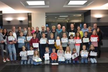 Die Kinder präsentieren stolz ihre kreativen Bilder vor den Eltern, der Werkleitung und dem Betriebsrat.  