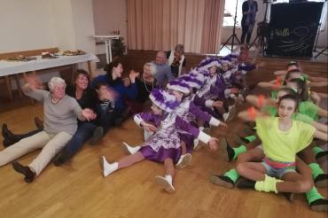 Senioren und Tanzgarde sitzen auf dem Boden