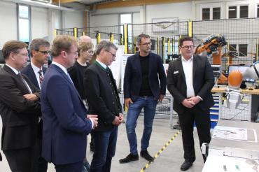 Das Bild zeigt OB-Kandidat Höhn mit Staatsminister Sibler, weiteren Vertretern der CSU und den Verantwortlichen des TCW beim Besuch der Roboterhalle.