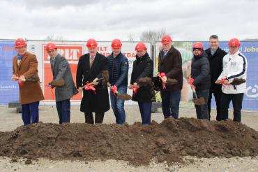 9 Männer mit Helm und Spaten schaufeln Erde