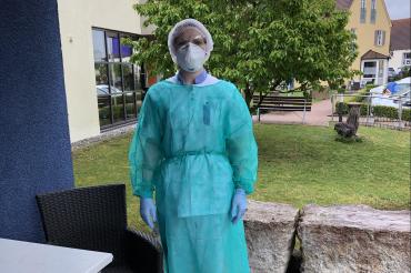 Das Bild zeigt Jaqueline Trost in Schutzausrüstung an ihrem Arbeitsplatz der Diakonie in Harburg. 