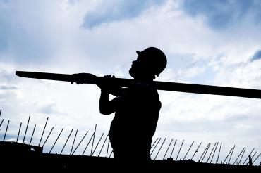 Schatten eines Bauarbeiters mit Helm und Holzlatte