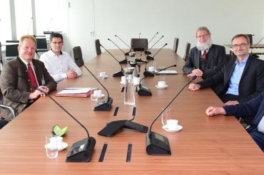 Sechs Personen sitzen an einem Konferenztisch