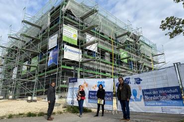 Vier Personen vor eingerüstetem Büroneubau