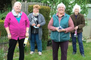 Vier Damen halten Gesichtsschutzmasken