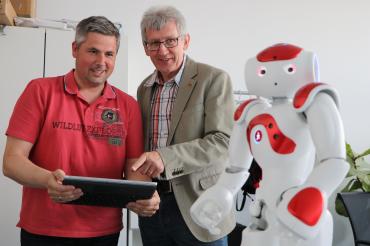 Zwei Männer mit Tablet und Roboter