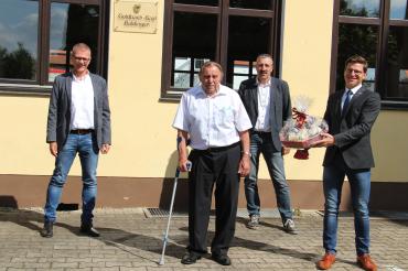 Vier Männer stehen vor Goldbachsaal Baldingen, einer mit Präsentkorb