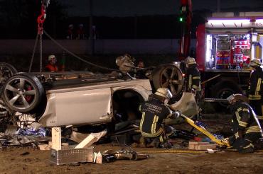 Zerstörter Pkw mit Feuerwehrleuten