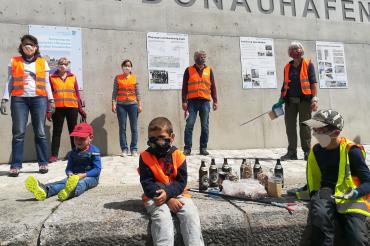 Fünf Erwachsene und drei Kinder mit Masken und Warnwesten vor Ufermauer Donauwörth