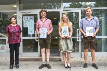 Lehrerin mit drei Landwirtschaftsschulen-Absolventen in Tracht, mit Urkunden