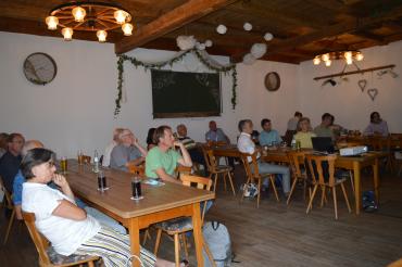 Personen sitzen im Wirtshaus und hören einen Vortrag