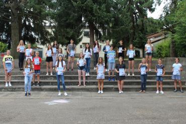 23 Kinder mit Urkunden auf Treppe vor Bäumen, mit Sicherheitsabstand