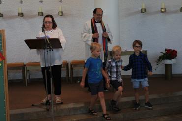 Drei Kinder mit Pfarrer und eine Rednerin