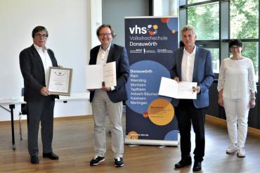Fünf Männer und eine Frau, drei Männer mit Urkunde, dahinter Roll-Up der VHS Donauwörth