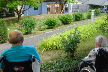 Zwei Senioren hören drei Alphornbläsern zu