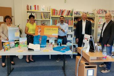 Fünf Personen stehen mit Scheck in Bücherei