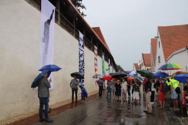 Fahnen an Nördlinger Stadtmauer, davor Publikum mit Regenschirmen