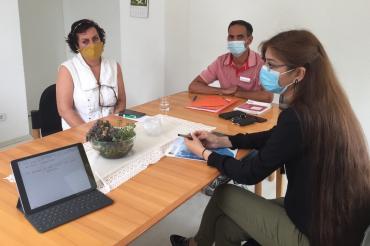 Drei Personen mit Mundschutz sitzen an einem Tisch