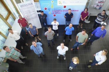 Studenten stehen in Raum vor Roll-ups, mit Abstand