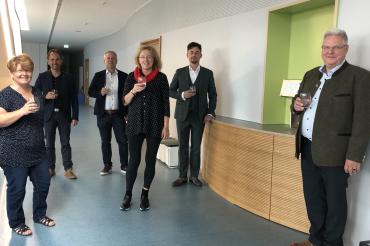 Personen mit Glas in der Hand stehen in einem Flur