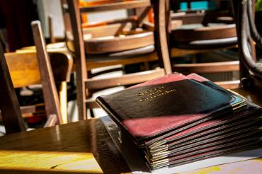 Das Bild zeigt ein leeres Restaurant und Speißekarten auf einem Tisch liegen