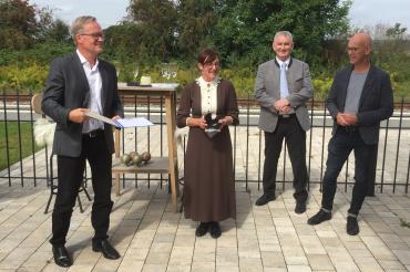 Vier Personen, einer übergibt Auszeichnung an Dame